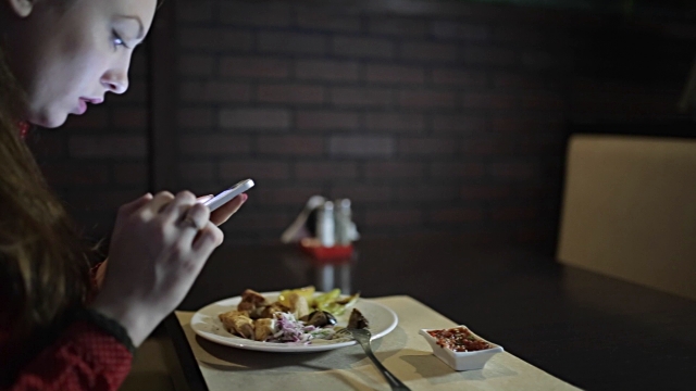 stock-video-75216323-the-girl-in-the-red-dress-sits-at-a-table-in-the-restaurant-and-use-the-phone
